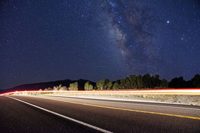 Light trails on road against sky at night