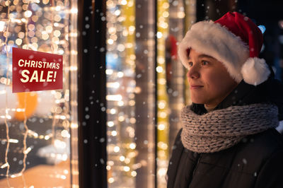 Smiling boy looking inside store from outdoors at night