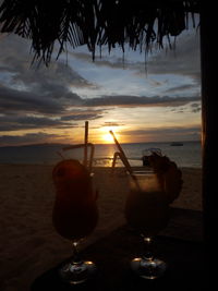 Close-up of beer on beach at sunset
