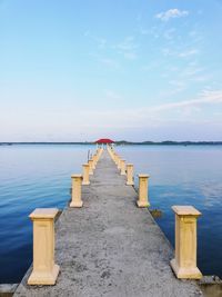 Wooden posts on pier over sea against sky