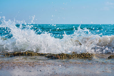 Waves splashing on shore against sky