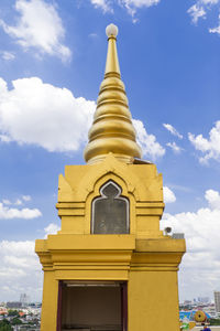 Low angle view of gold building against cloudy sky