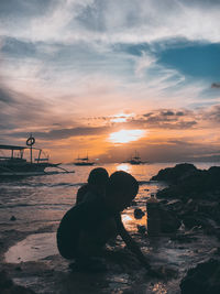 Silhouette woman looking at sea against sky during sunset