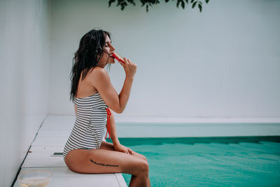 Woman sitting in swimming pool against sea