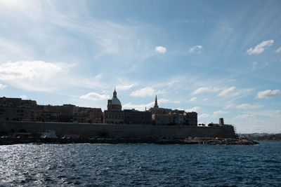 Buildings by sea against sky in city