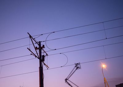 Low angle view of silhouette electricity pylon against clear sky