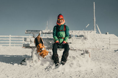 Portrait of a girl standing on snow with her dog