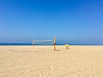 Volleyball net on beach against clear blue sky