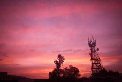 Low angle view of silhouette communications tower against sky during sunset