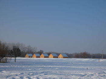 Snow covered field against clear sky during winter