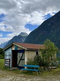 House on field by mountains against sky