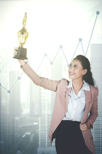 Businesswoman holding trophy in office