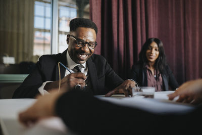 Happy mature businessman examining documents sitting in board room at office