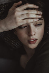 Close-up of woman with headache looking away while lying on sofa