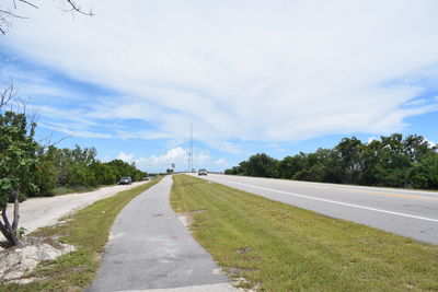 Empty road amidst trees against sky