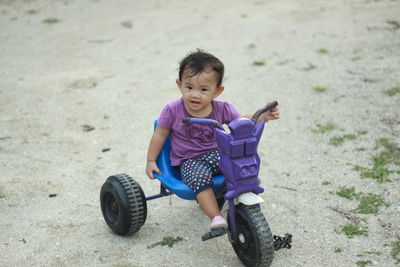 Portrait of cute girl sitting on tricycle