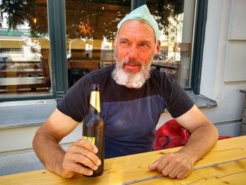 Portrait of man holding food while sitting on table