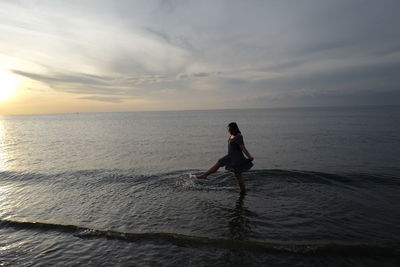 Full length of man on beach against sky during sunset