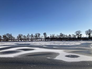 Scenic view of snow covered landscape against clear blue sky