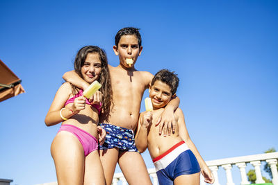 Portrait of smiling friends against clear blue sky