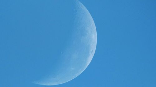 Low angle view of moon against blue sky