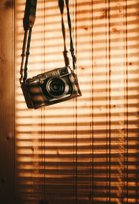 Close-up of camera hanging against wood