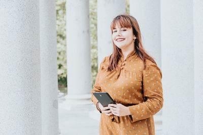 Portrait of young woman standing against wall