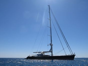 Sailboat sailing on sea against blue sky