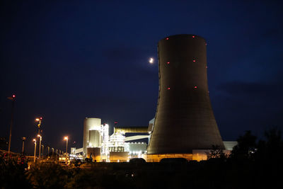 Low angle view of illuminated factory against sky at night