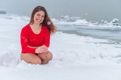 Portrait of young woman standing on snow covered field