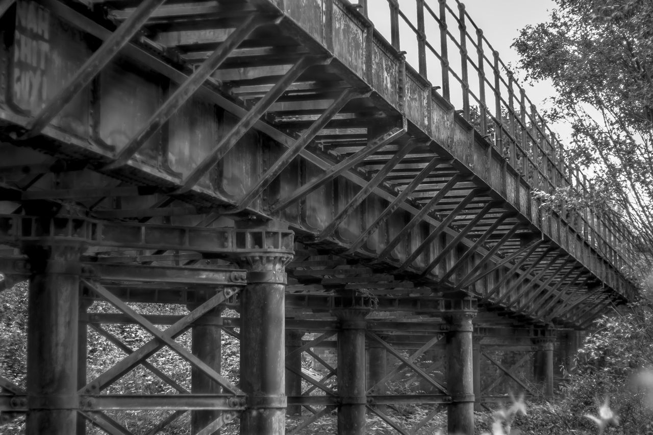 built structure, architecture, connection, low angle view, bridge - man made structure, metal, railing, engineering, metallic, bridge, day, footbridge, sky, building exterior, no people, outdoors, clear sky, tree, sunlight, support