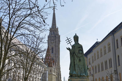 Low angle view of statue amidst buildings against sky