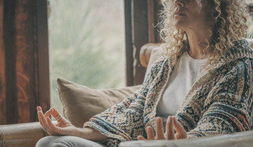 Midsection of woman meditating at home