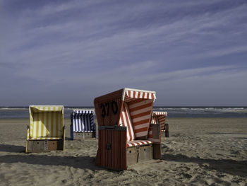 Chairs on beach chair by sea against sky