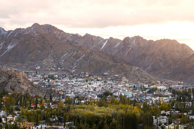 Aerial view of townscape and mountains against sky