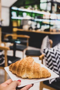 Close-up of hand holding bread in plate on table