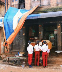 Full length rear view of school girls standing near shop in city