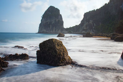 Rock formation on beach against sky