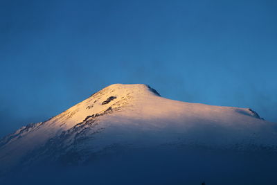 Scenic view of volcanic mountain against clear blue sky