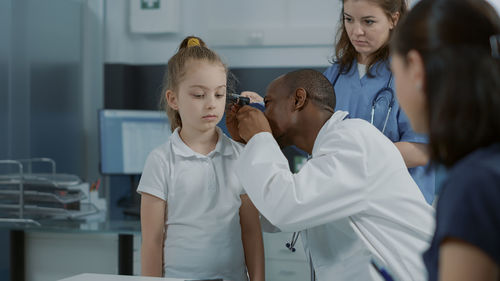 Doctor examining girl ear in clinic