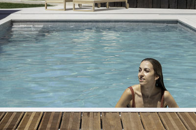 Happy young woman smiling while enjoying the swimming time in the pool in summer day with copy space