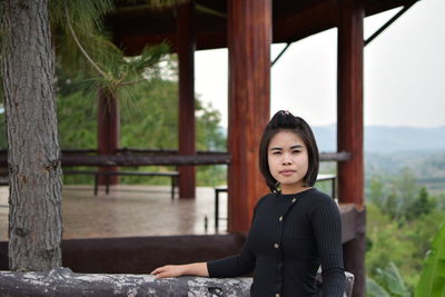 Portrait of young woman standing by railing on observation point