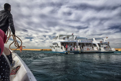 People on boat in sea against sky