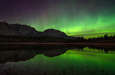 Northern lights reflected in still pong with mountain 