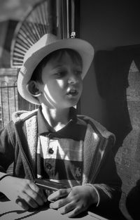 Boy wearing hat looking away in train