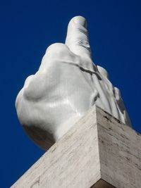 Low angle view of statue against building against blue sky