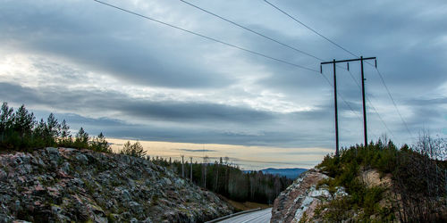 Electricity pylon against cloudy sky