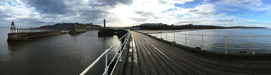 Pier on sea against cloudy sky