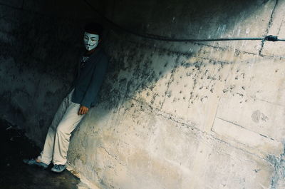 Man wearing mask while standing against wall