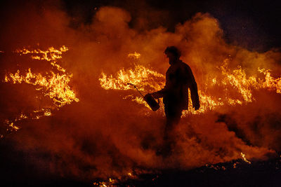Firefighter with a drip torch walks through a wildfire in australia